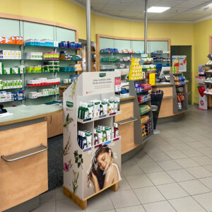 Innenansicht der HV-Tische der Apotheke am Margaretenhof. Hinter den Theken sind Medikamente auf Wandregalen und ein Aufsteller davor