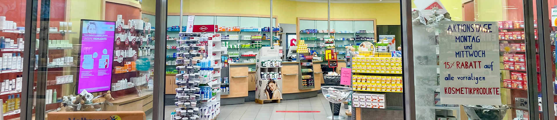 Offene Glastür und Schaufenster mit Blick auf den Verkaufsraum der Apotheke am Margaretenhof